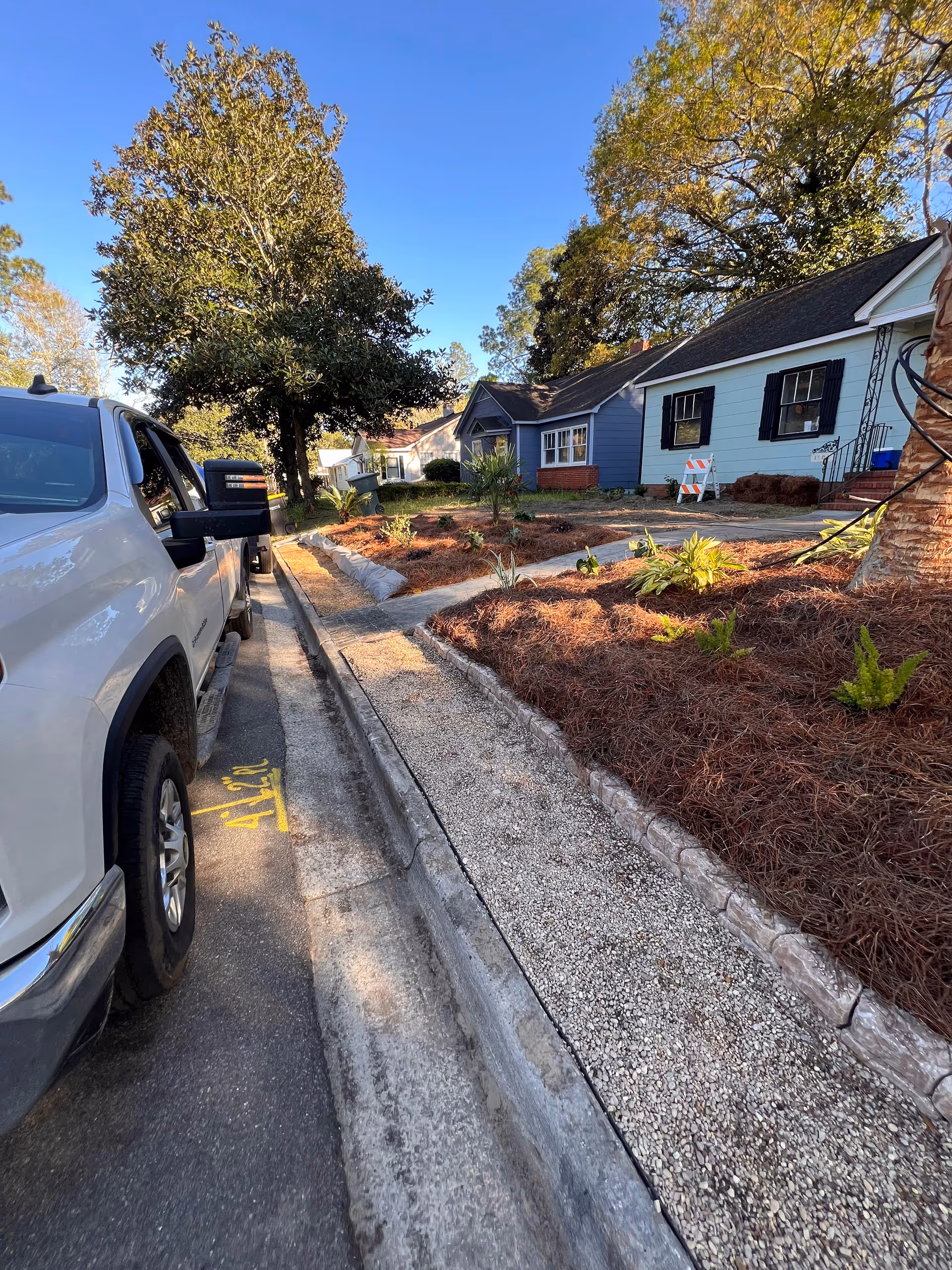 Exterior view of a blue, single-story senior home with landscaped front yard and a parked SUV