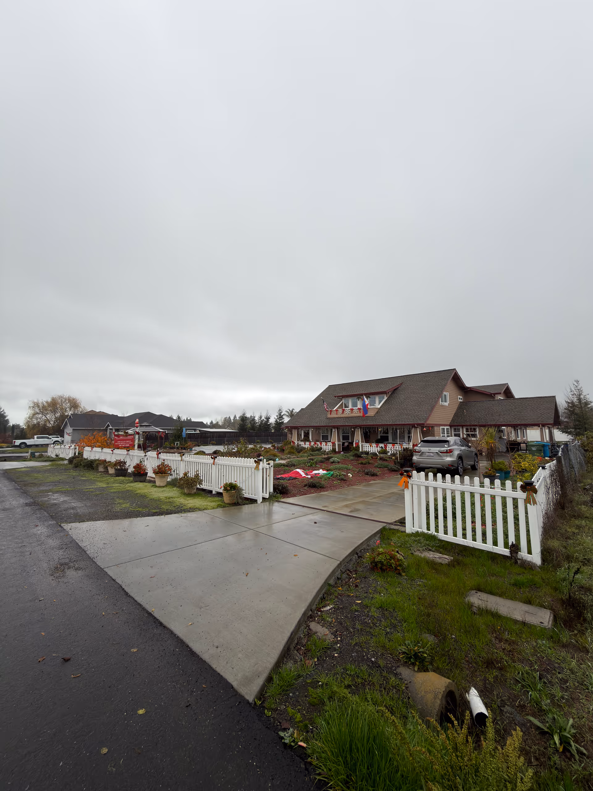 Exterior view of Penngrove Gardens with a white picket fence and garden beds.