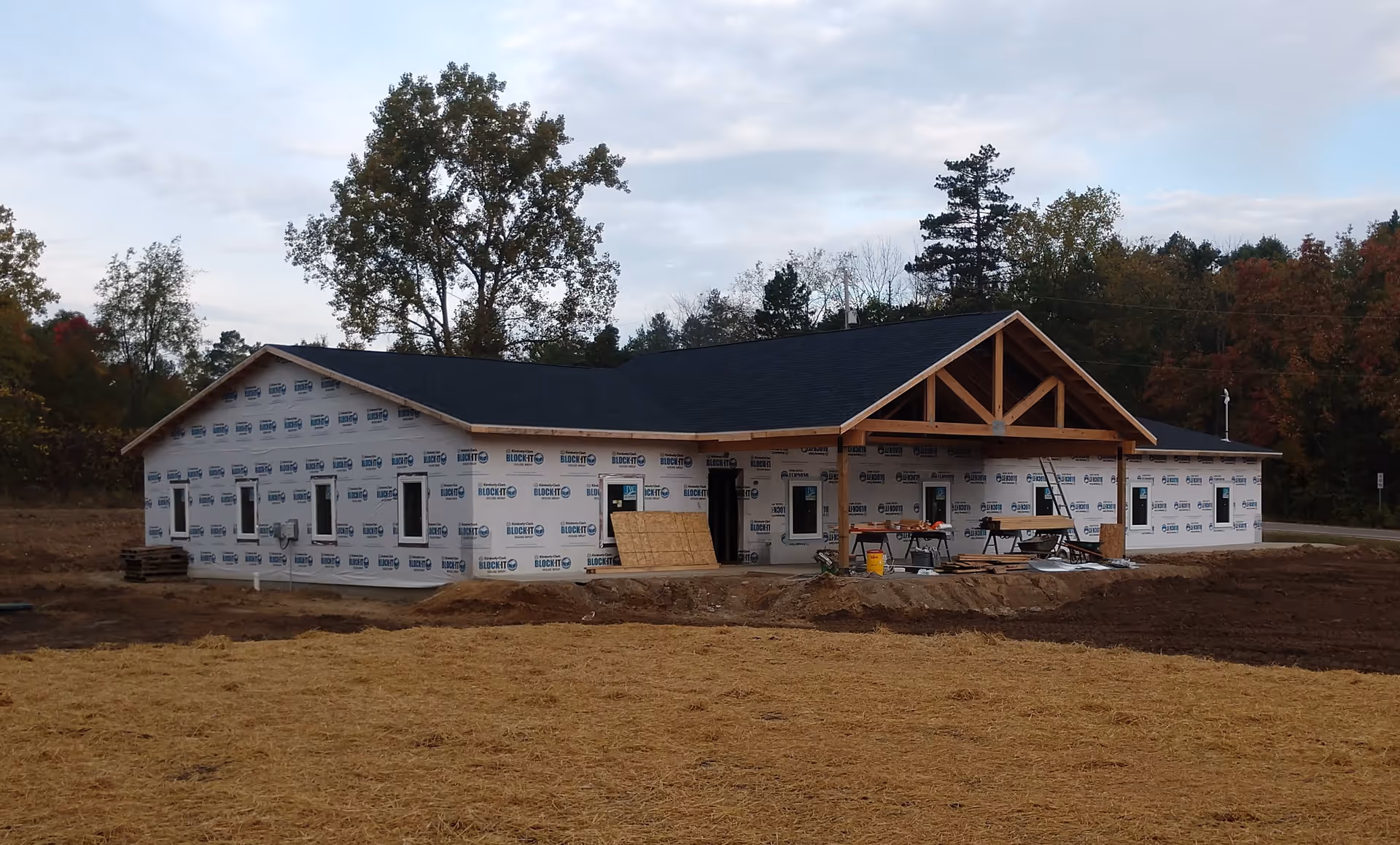 Single-story facility under construction with wrapped exterior and a wooden front entrance
