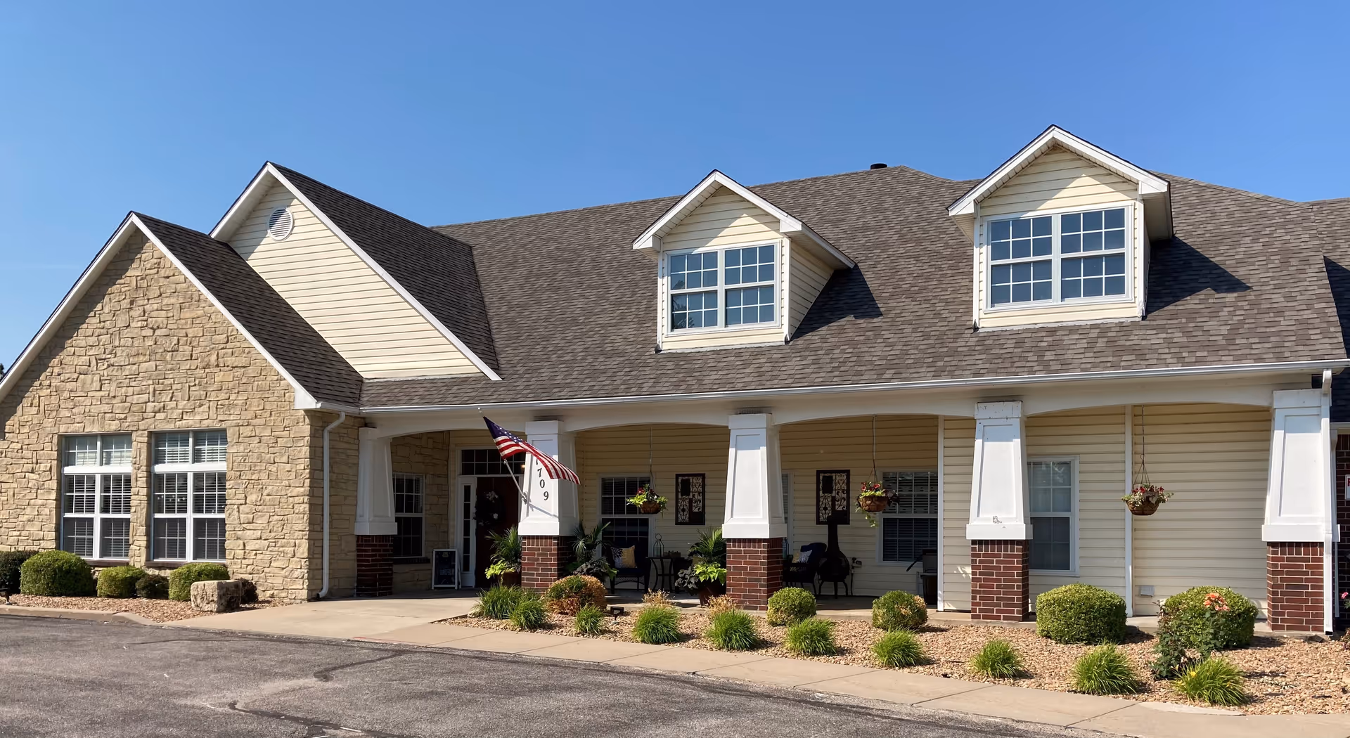 Single-story senior living facility exterior with covered porch, stone accents, and landscaped front.