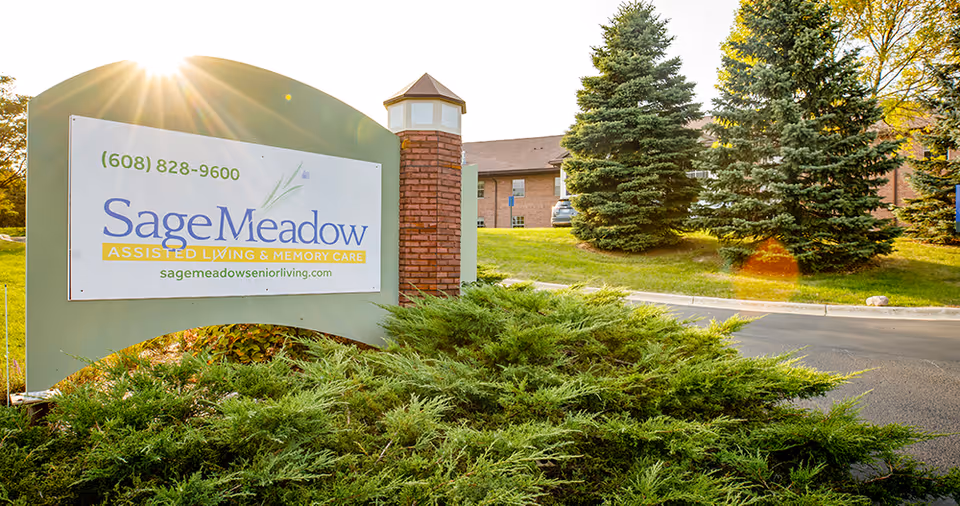 Sage Meadow sign at the facility entrance surrounded by shrubs and trees.