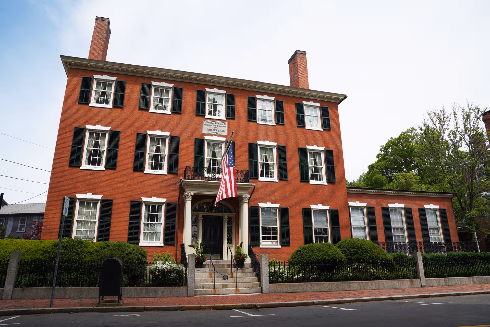 John Bertram House exterior: red brick building with green shutters and American flag.