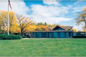 Exterior view of Cedar Manor Nursing & Rehabilitation Center with lawn and flag.