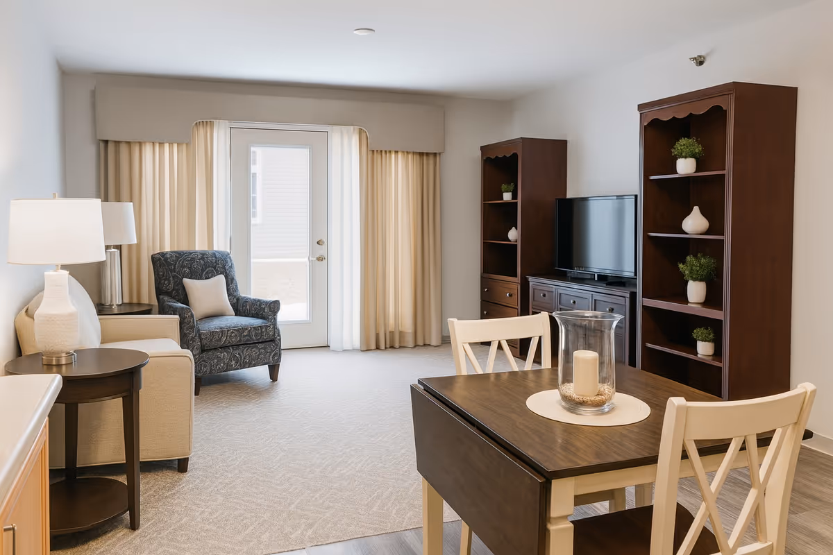 Bright living area with a dining table, armchairs, and a TV console.