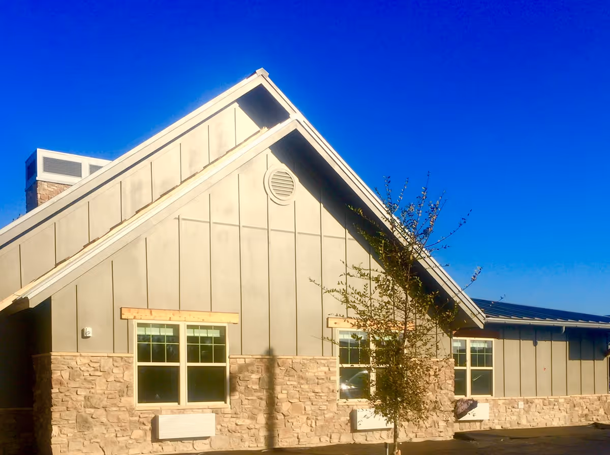Exterior view of The Crest San Angelo building with stone base and sloped roof.
