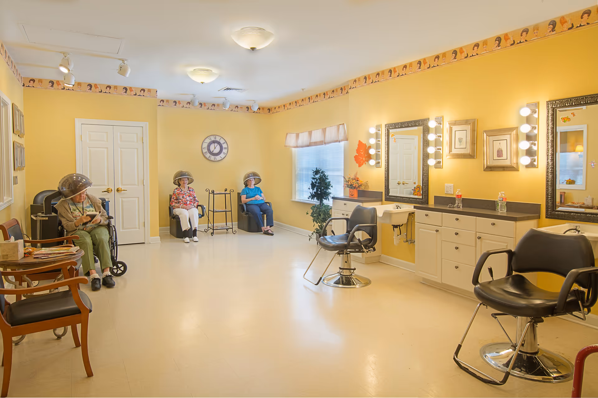 Bright yellow facility salon with mirrors, chairs, sinks, and several elderly residents seated.