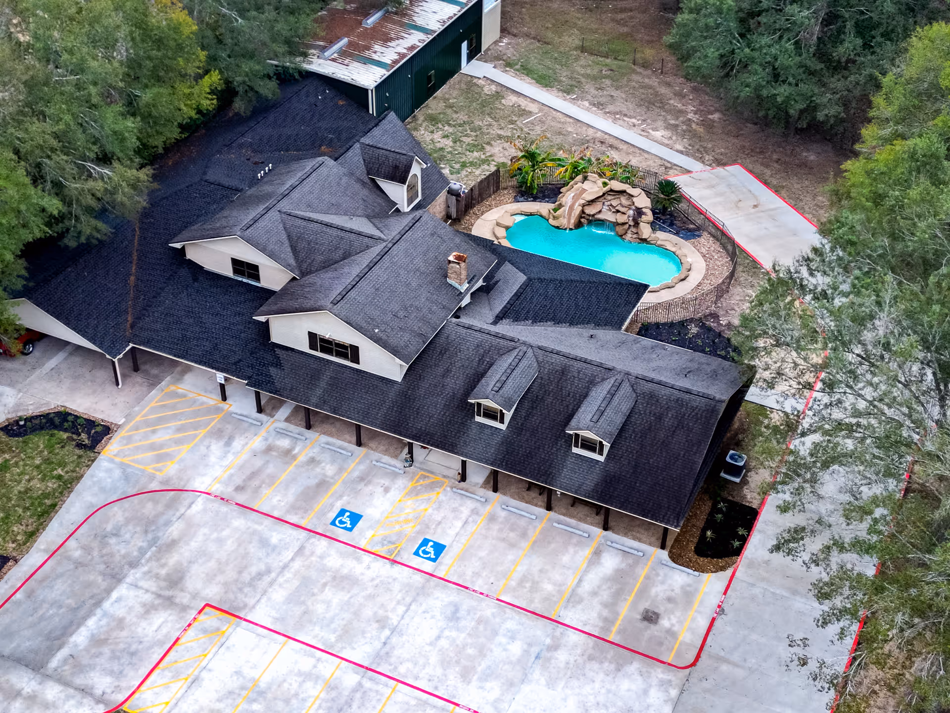 Aerial view of a senior living campus featuring a kidney-shaped pool and surrounding parking.