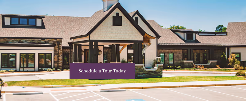 Exterior view of Westminster Memory Care building with entrance and purple schedule a tour today sign