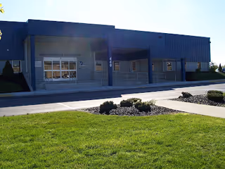 Blue building exterior with entrance steps and trimmed landscaping in front.