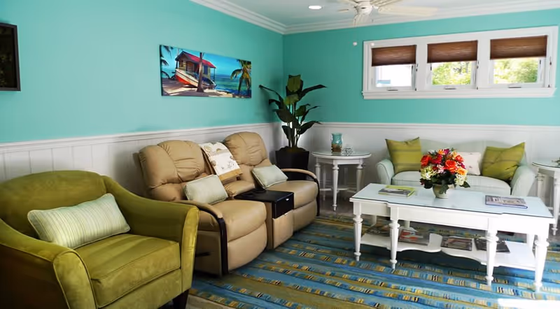 Bright turquoise lounge with teal walls, white trim, and colorful seating in a cozy living area.