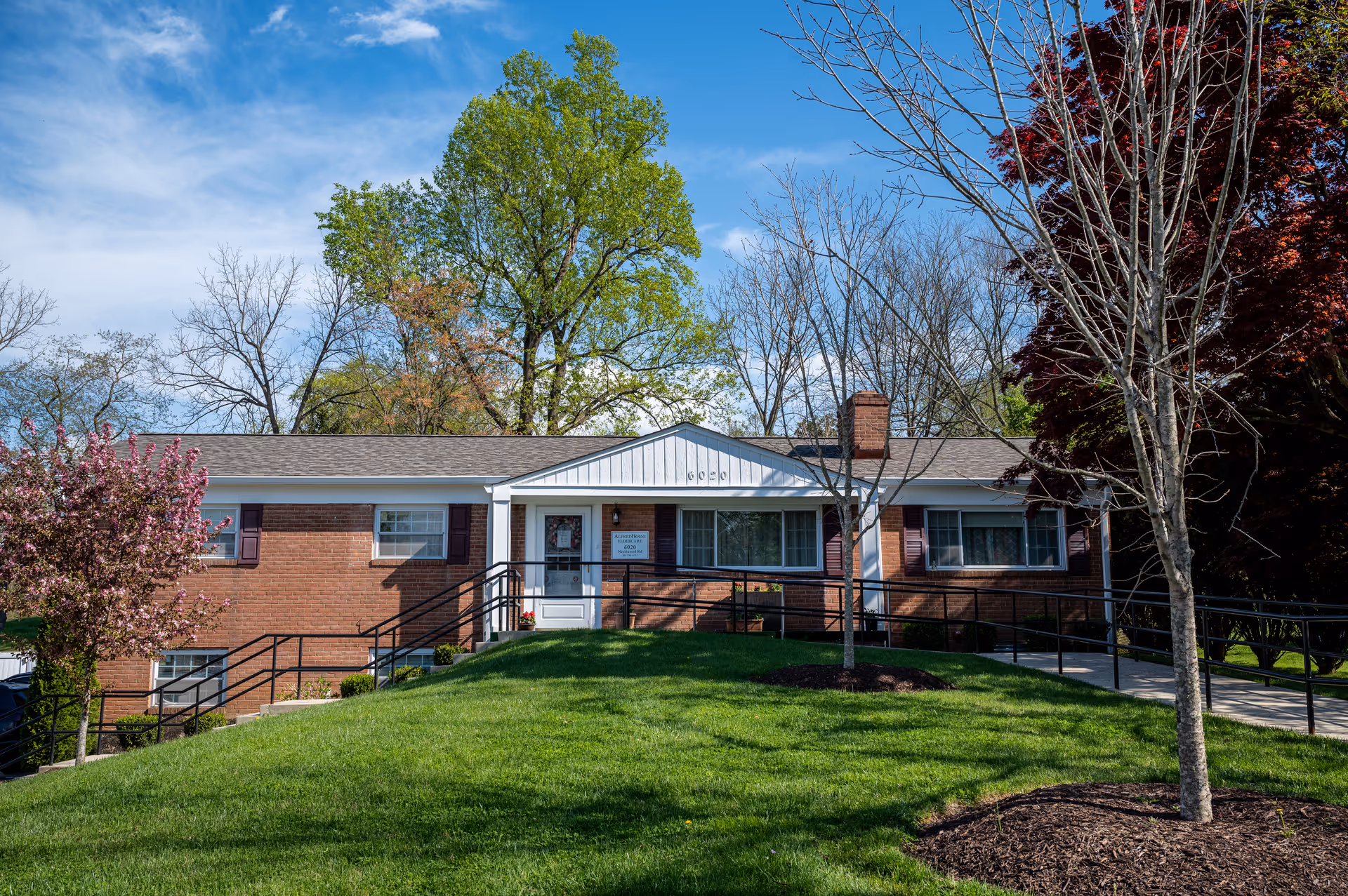 AlfredHouse II building with brick exterior, green lawn, and trees framing the front entrance.