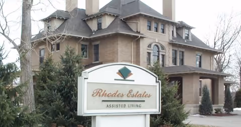 Exterior view of a multi-story senior living facility with a sign in front.