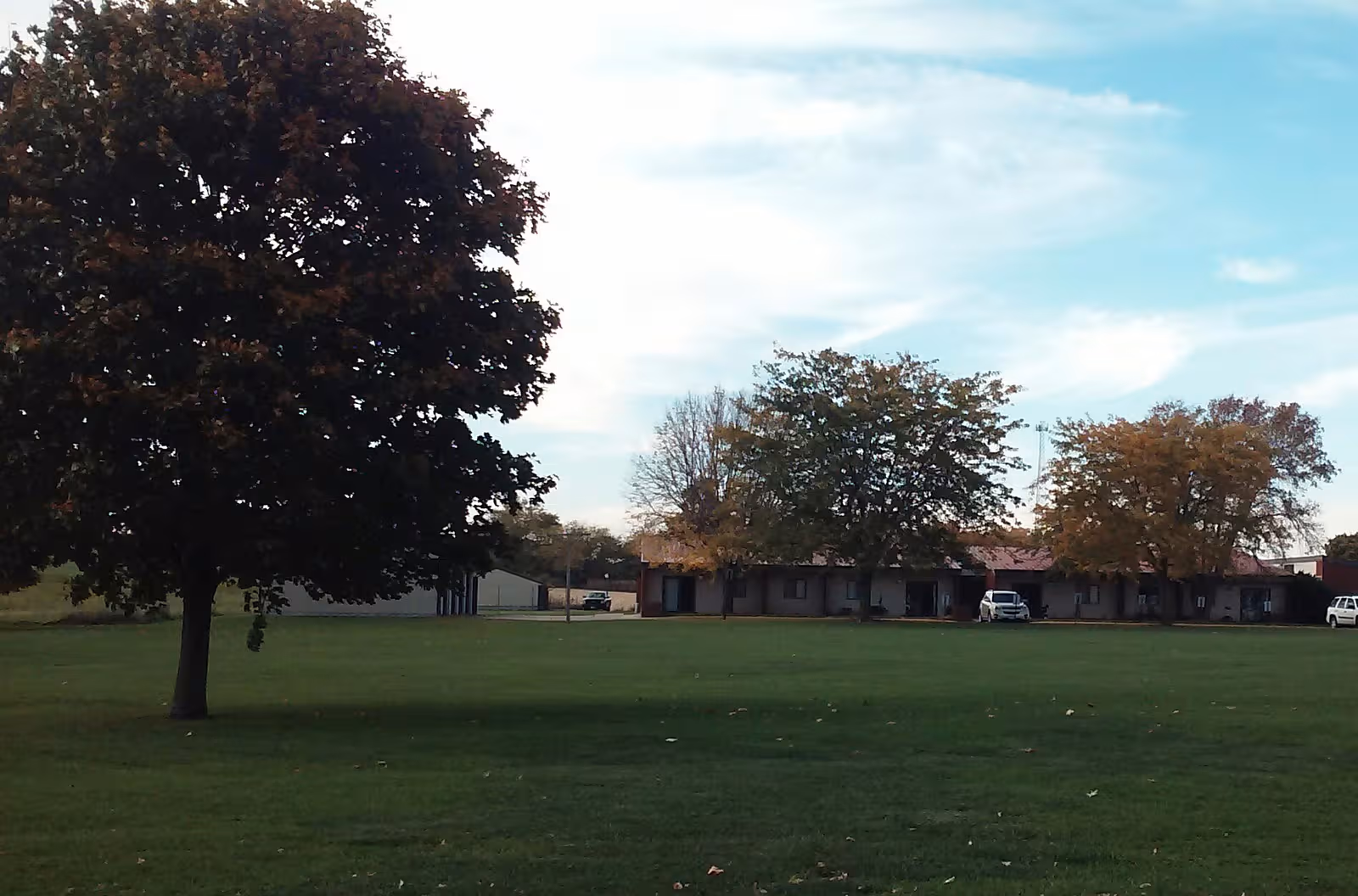 Front view of a single-story retirement center with a grassy lawn and trees.