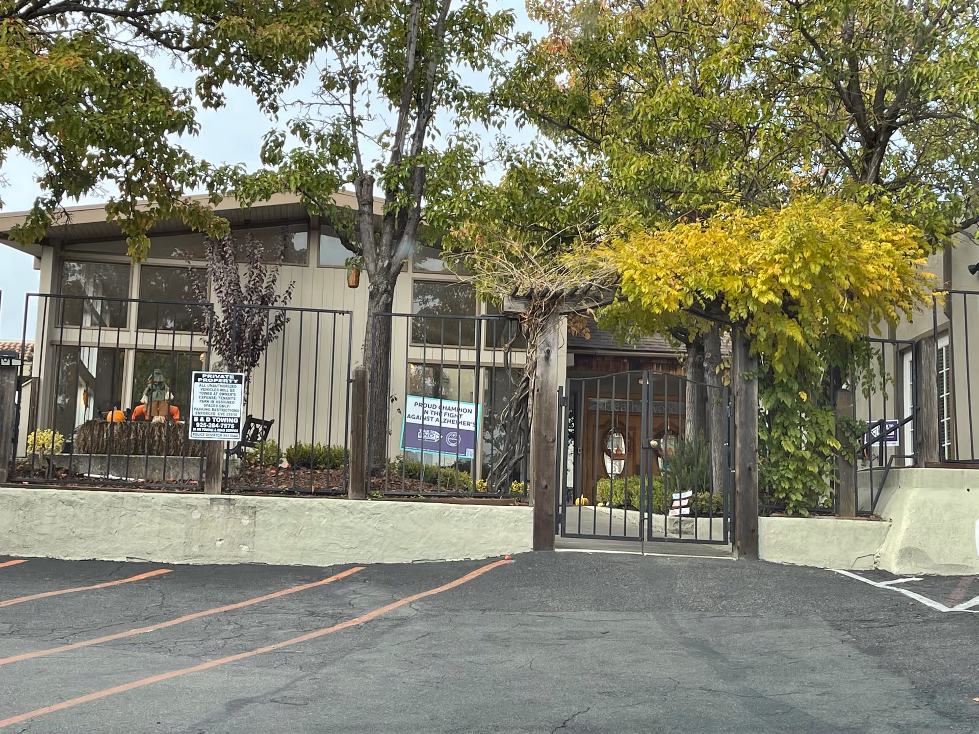 Front view of Heatherwood Memory Care with a gated entrance and trees.