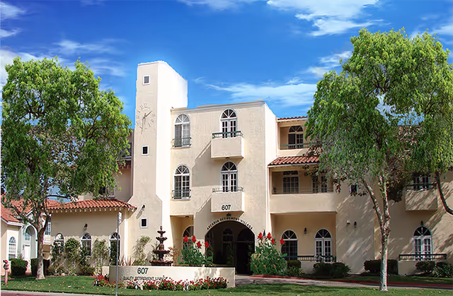 Beige Arcadia Retirement Village building with arches and a fountain surrounded by trees