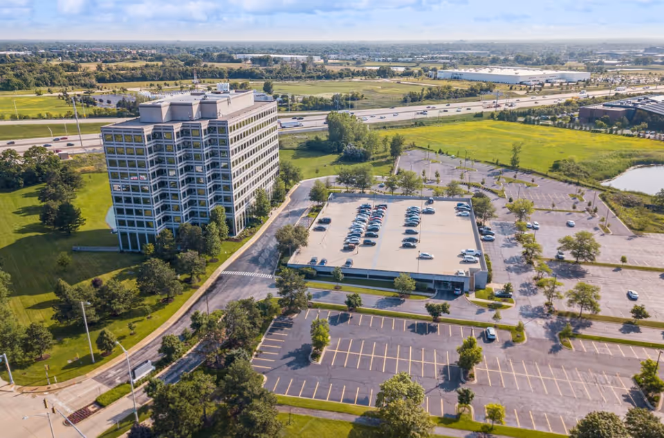 Aerial view of a large multi-story senior facility with surrounding parking and green fields.