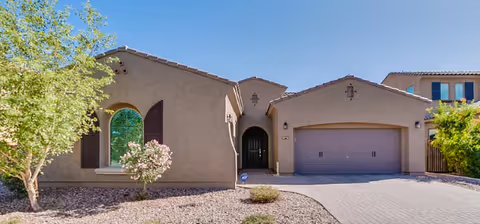 Front exterior of a single-story tan assisted living home with a driveway