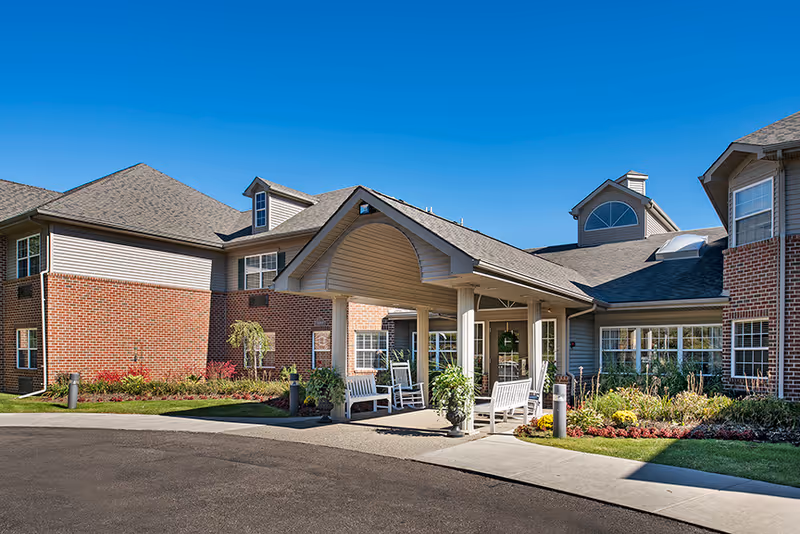 Exterior view of Towering Oaks AFC Residence entrance with landscaped garden and outdoor seating.