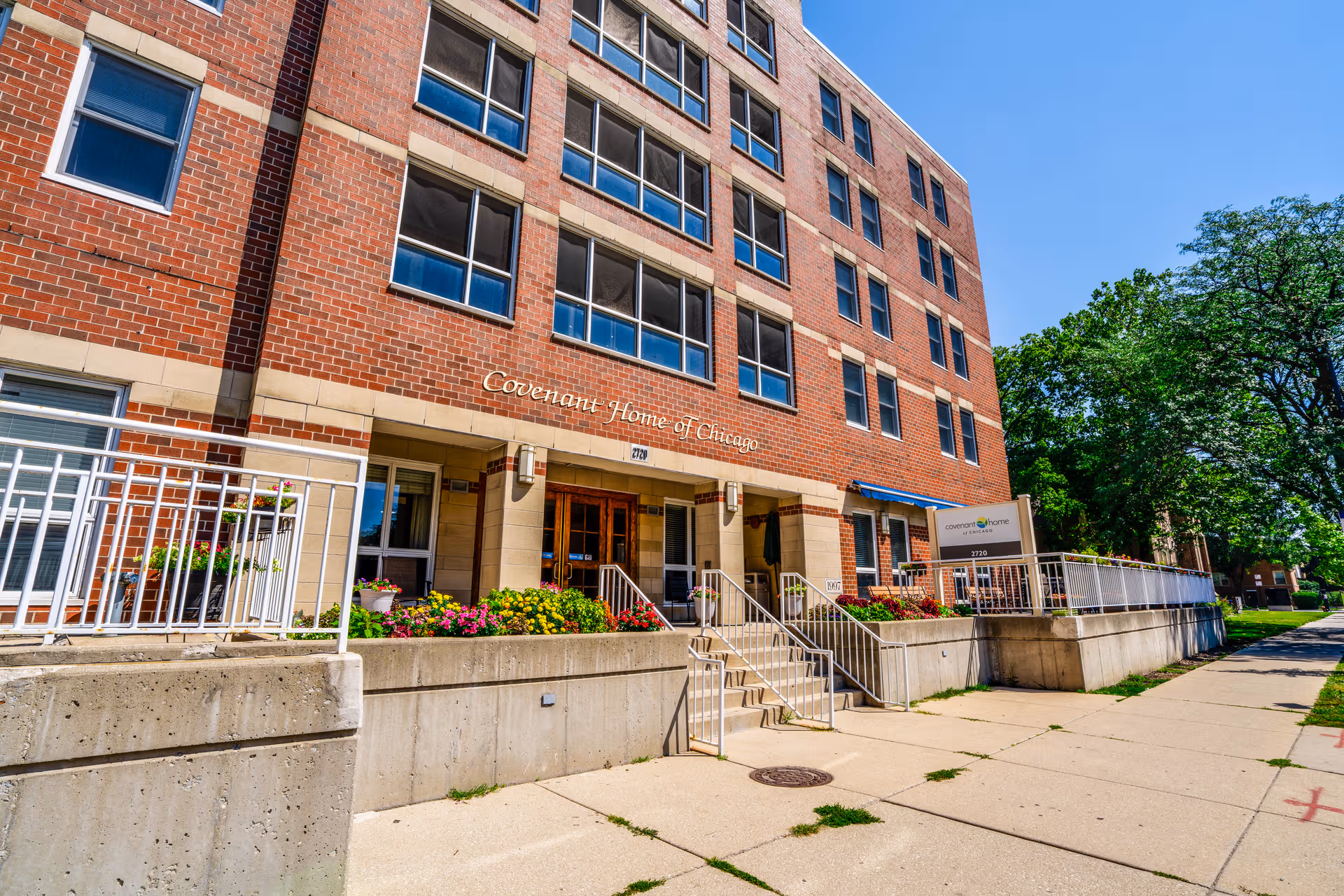 Brick Covenant Home of Chicago exterior with entrance, stairs, and flowering planters.