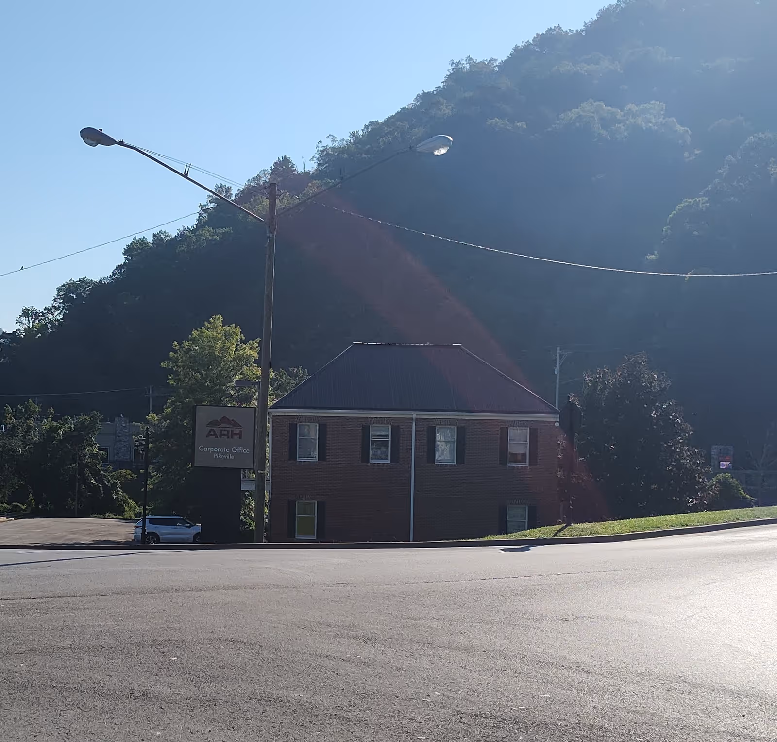Exterior view of a brick office building with ARH sign beside hillside.