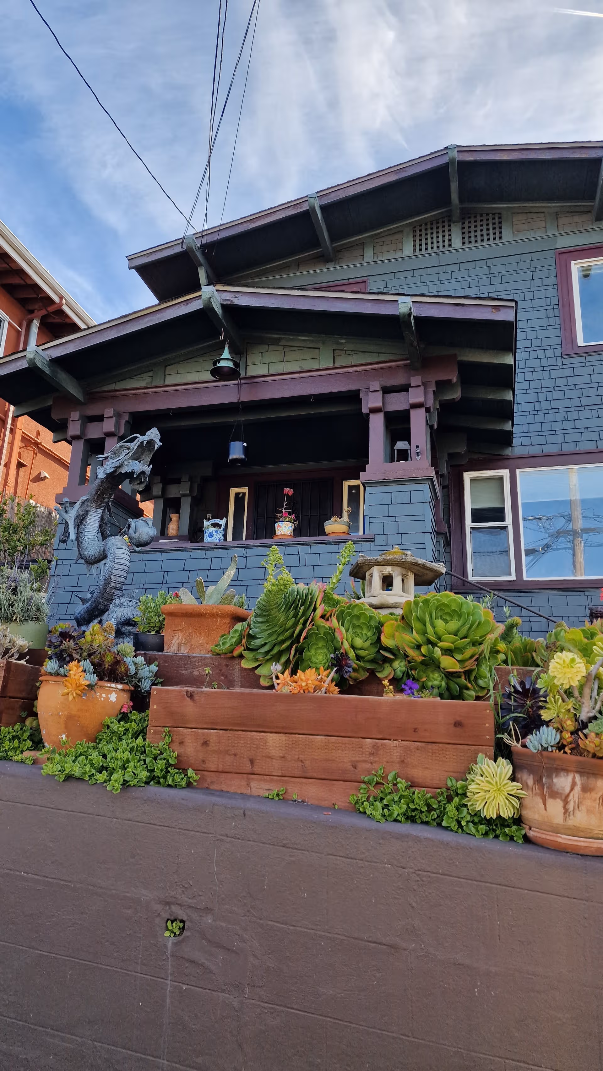 Craftsman-style building with a front porch, hanging lantern, and lush succulent garden.
