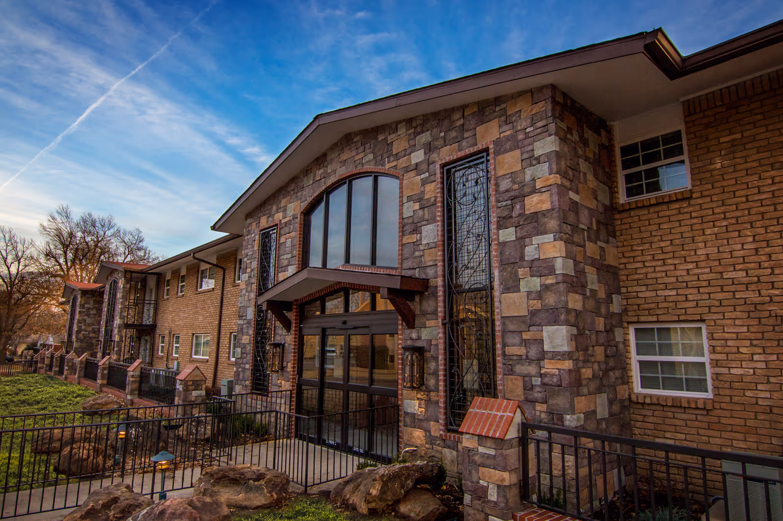 View of Scandia Retirement Community building exterior with brick, stone facade, and large arched entrance.