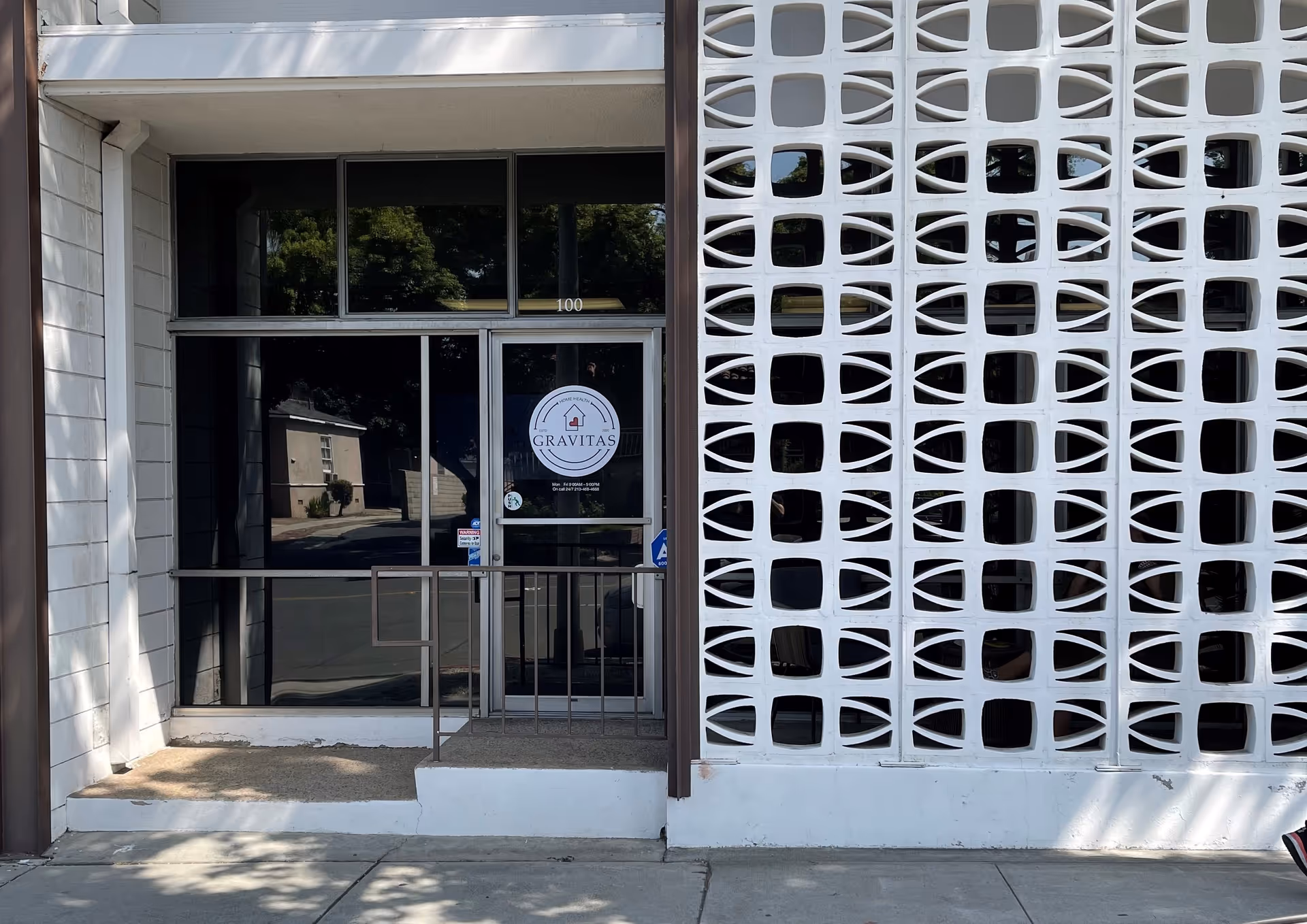 Front entrance of Gravitas Home Health Care with glass doors and decorative white wall.