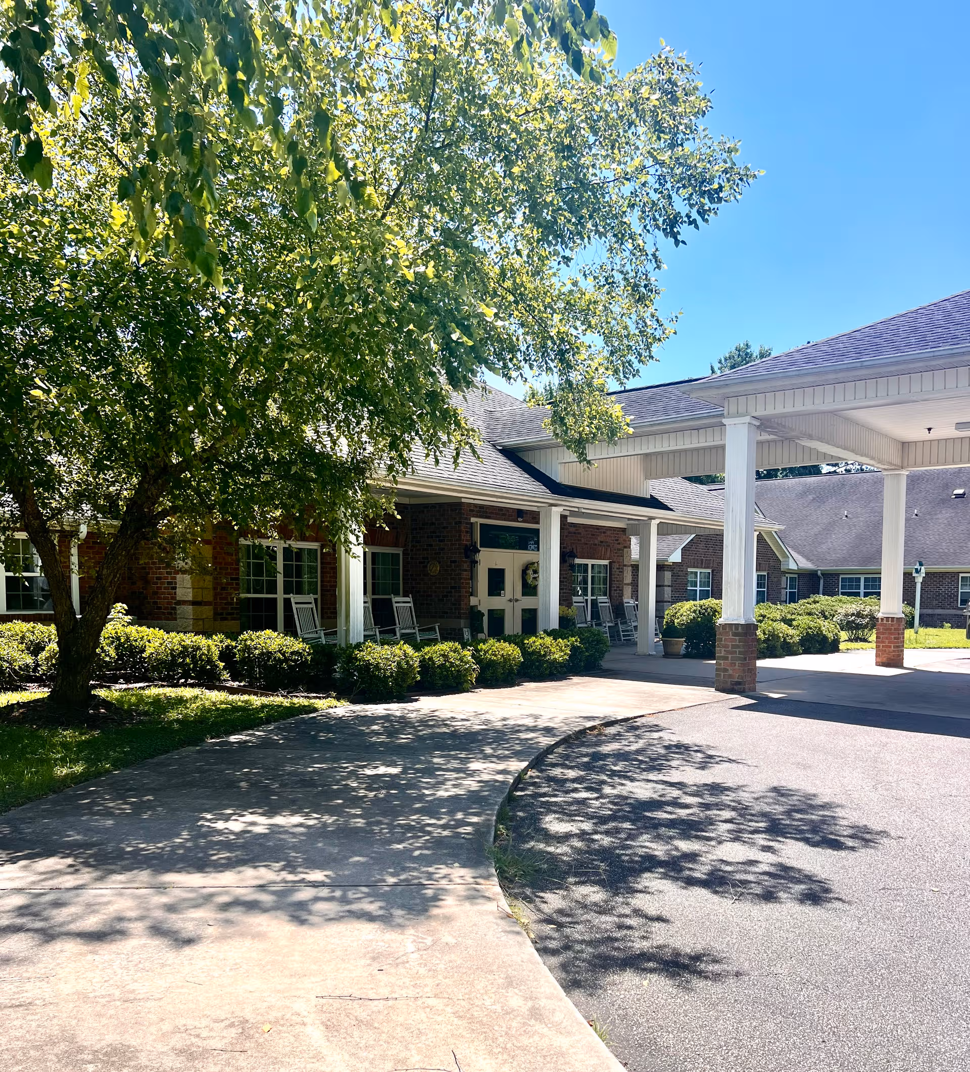 Sunny entrance to Prestwick Village Senior Living with brick facade and white portico.