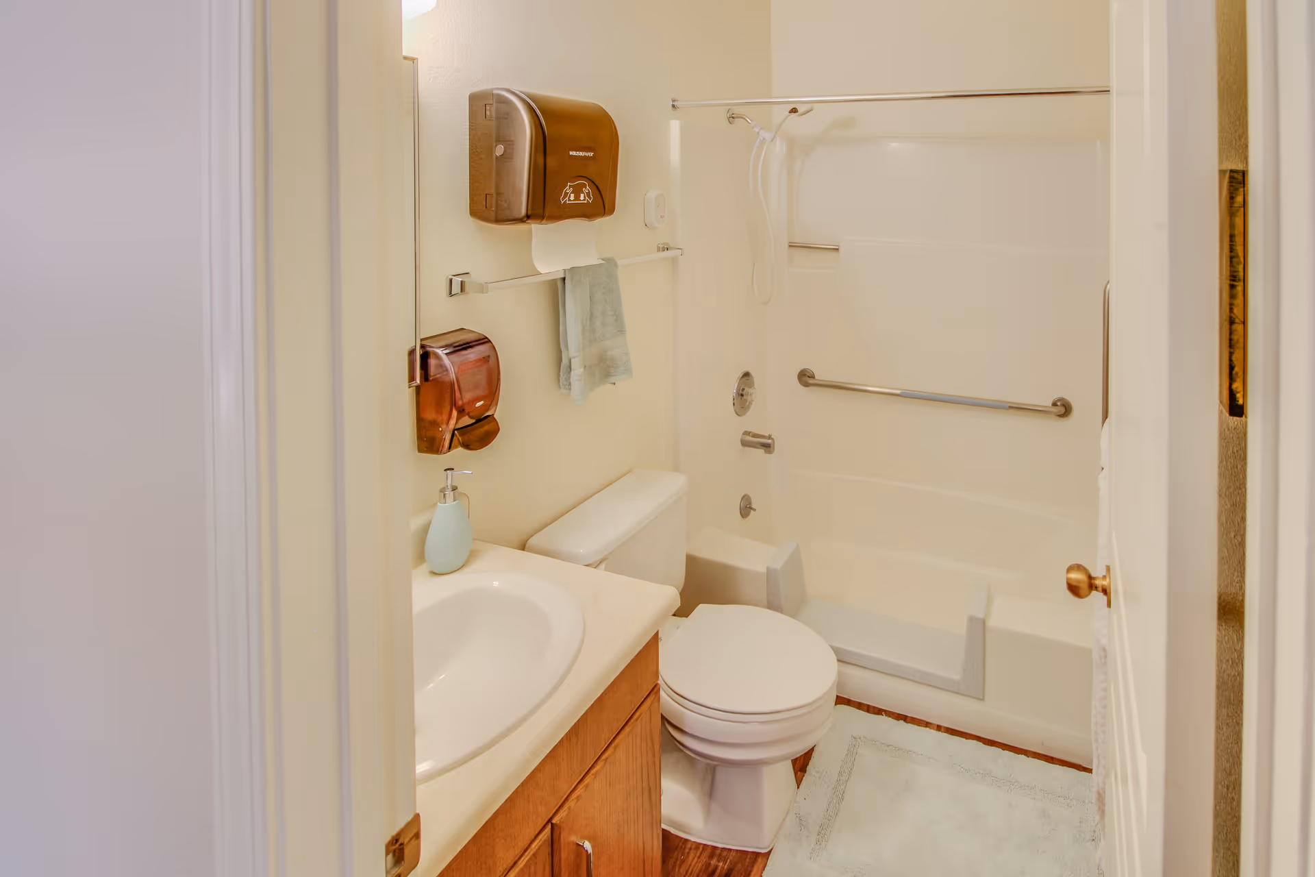 Compact bathroom in a senior facility with sink, toilet, and accessible tub.