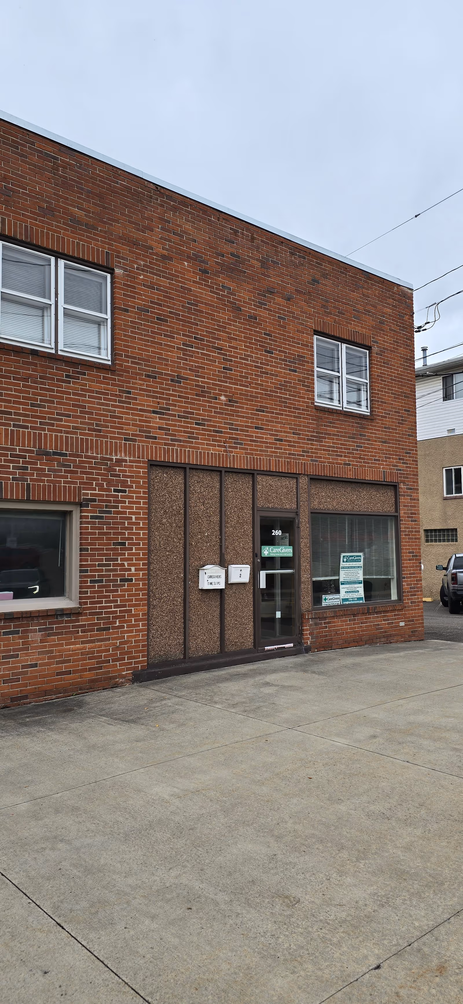 Brick building exterior with a glass entry door and two upper windows.