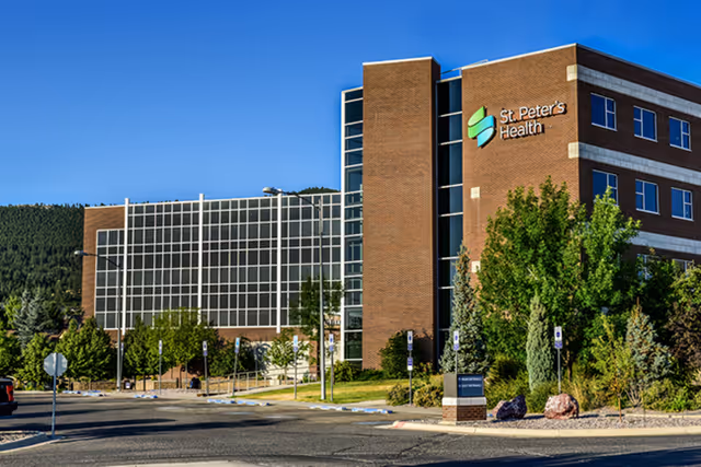 Exterior view of St. Peter's Health Hospice building with brick facade and glass atrium.