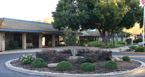 Exterior view of Park Merced Assisted Living with a circular landscaped island and building entrance.