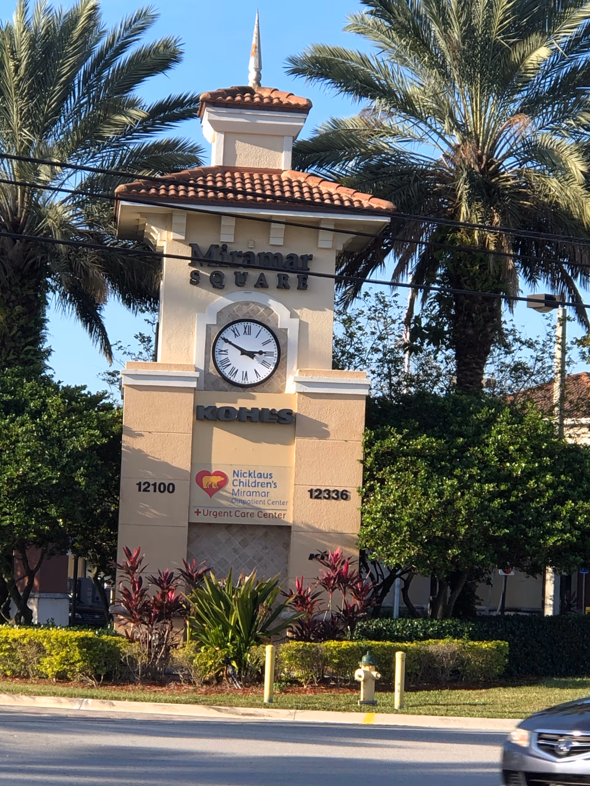 Exterior sign tower for Nicklaus Children's Miramar at a plaza with palm trees.