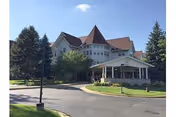 Exterior view of a large senior living facility with a curved driveway and front entrance.