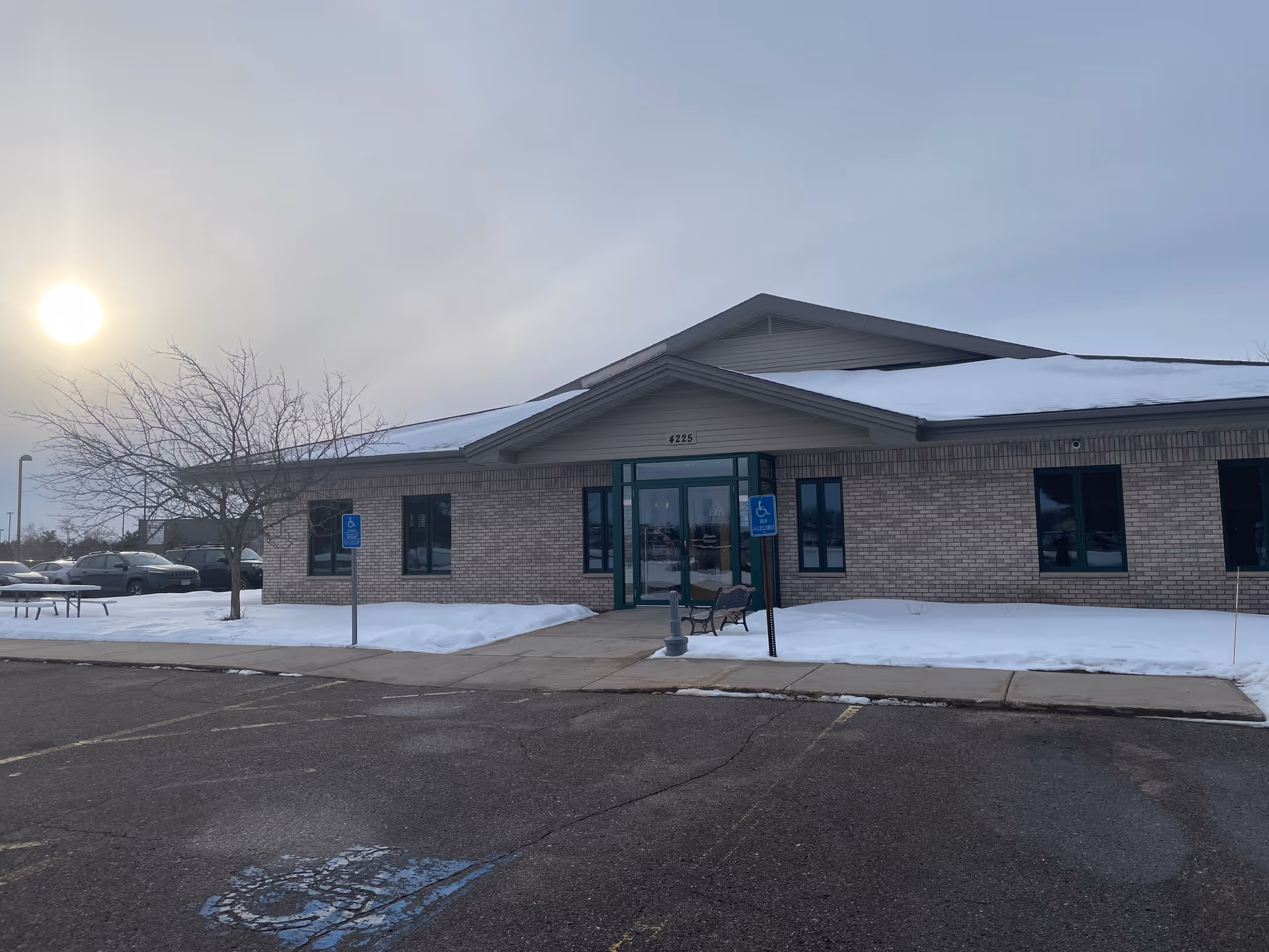 Exterior view of a brick building with a green entry and snow.