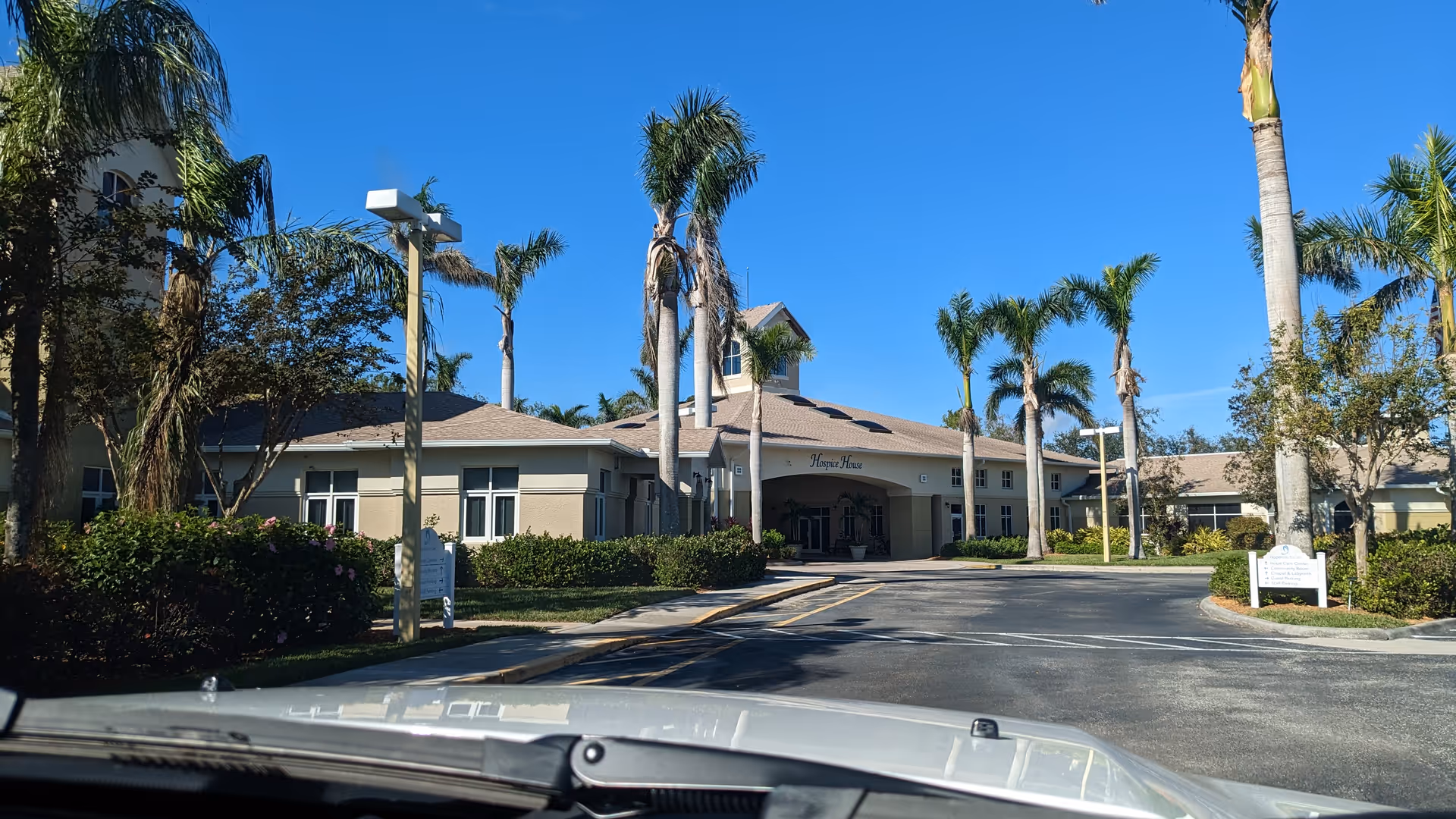 Exterior view of Hope Hospice entrance with palm trees and a driveway.