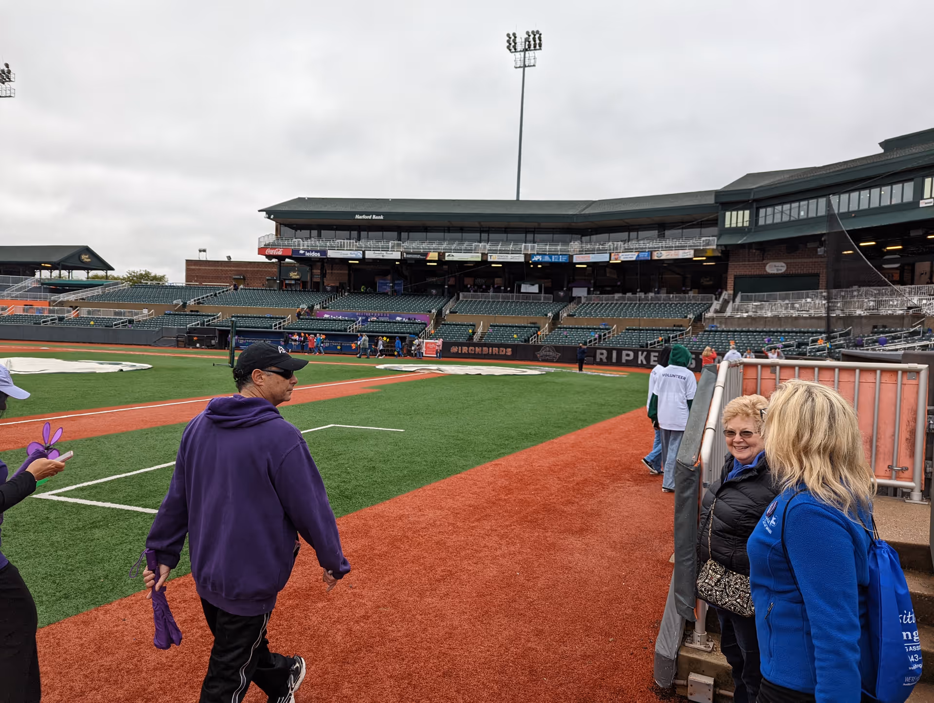 View of a baseball stadium field with fans near the dugout and seating