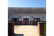 Front view of Hillside Manor Personal Care Home entrance with brick pillars and lamps.
