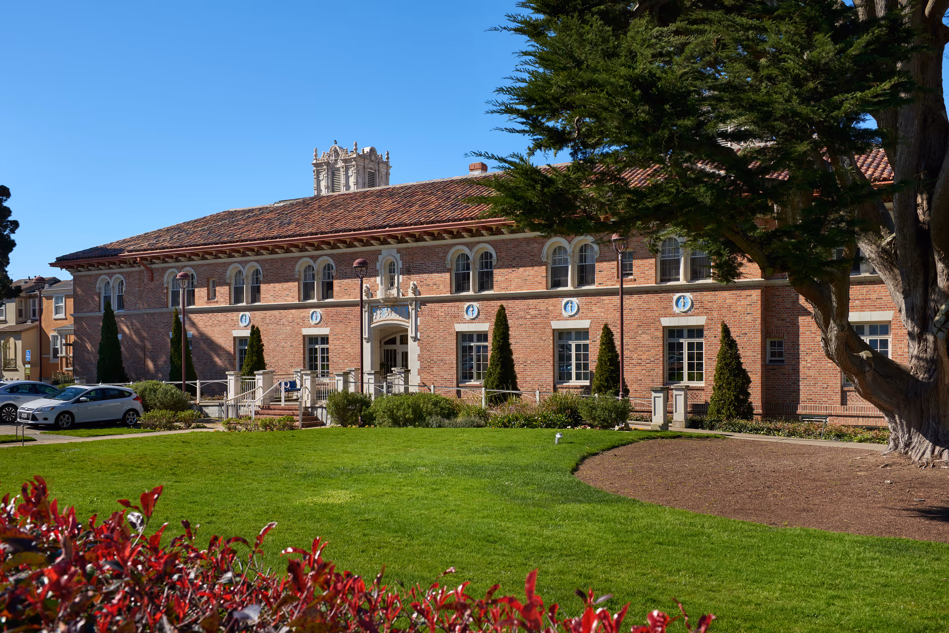 Exterior view of The Ivy at Golden Gate, brick building with arched windows and green lawn.