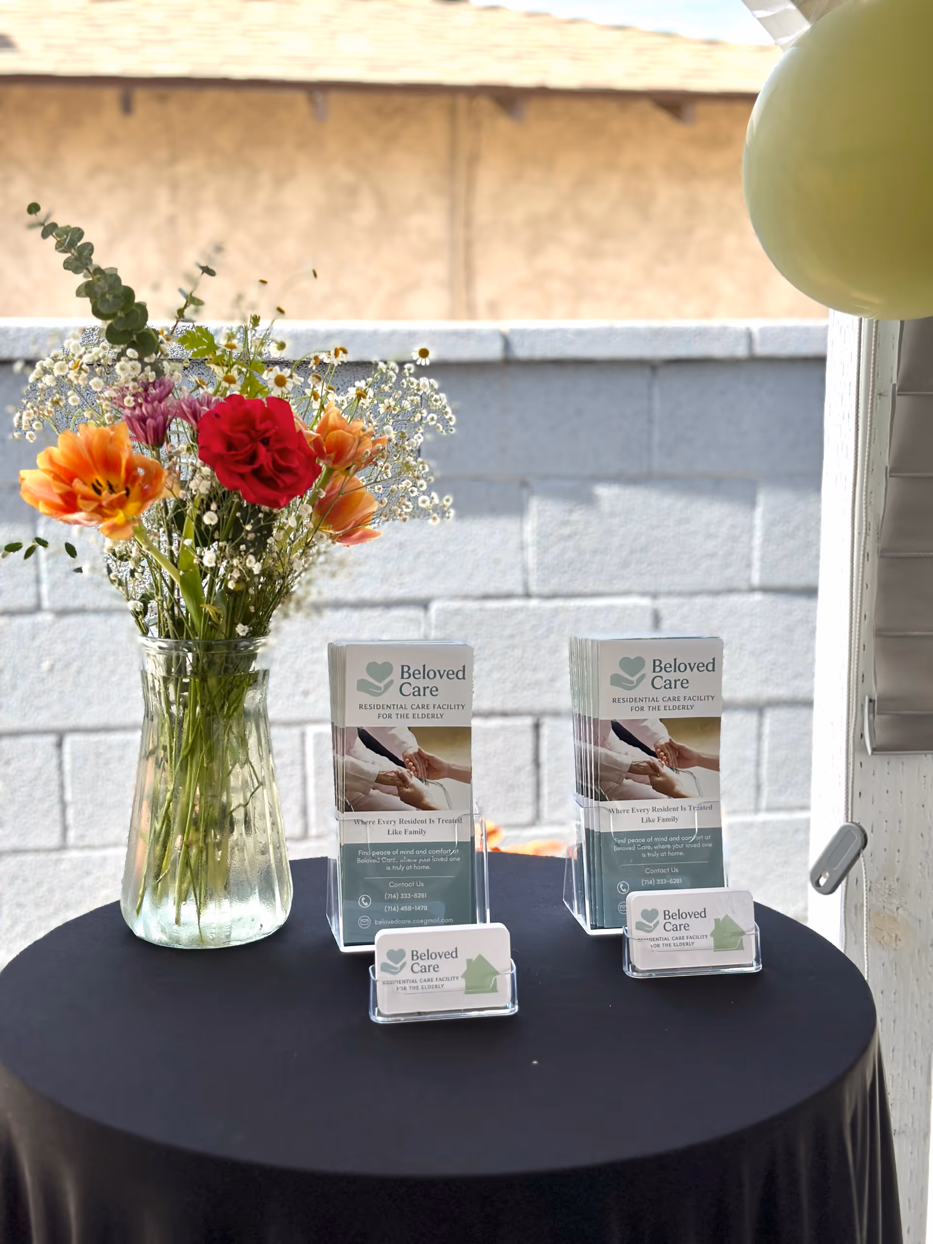 Table with a vase of flowers and Beloved Care brochures on display.