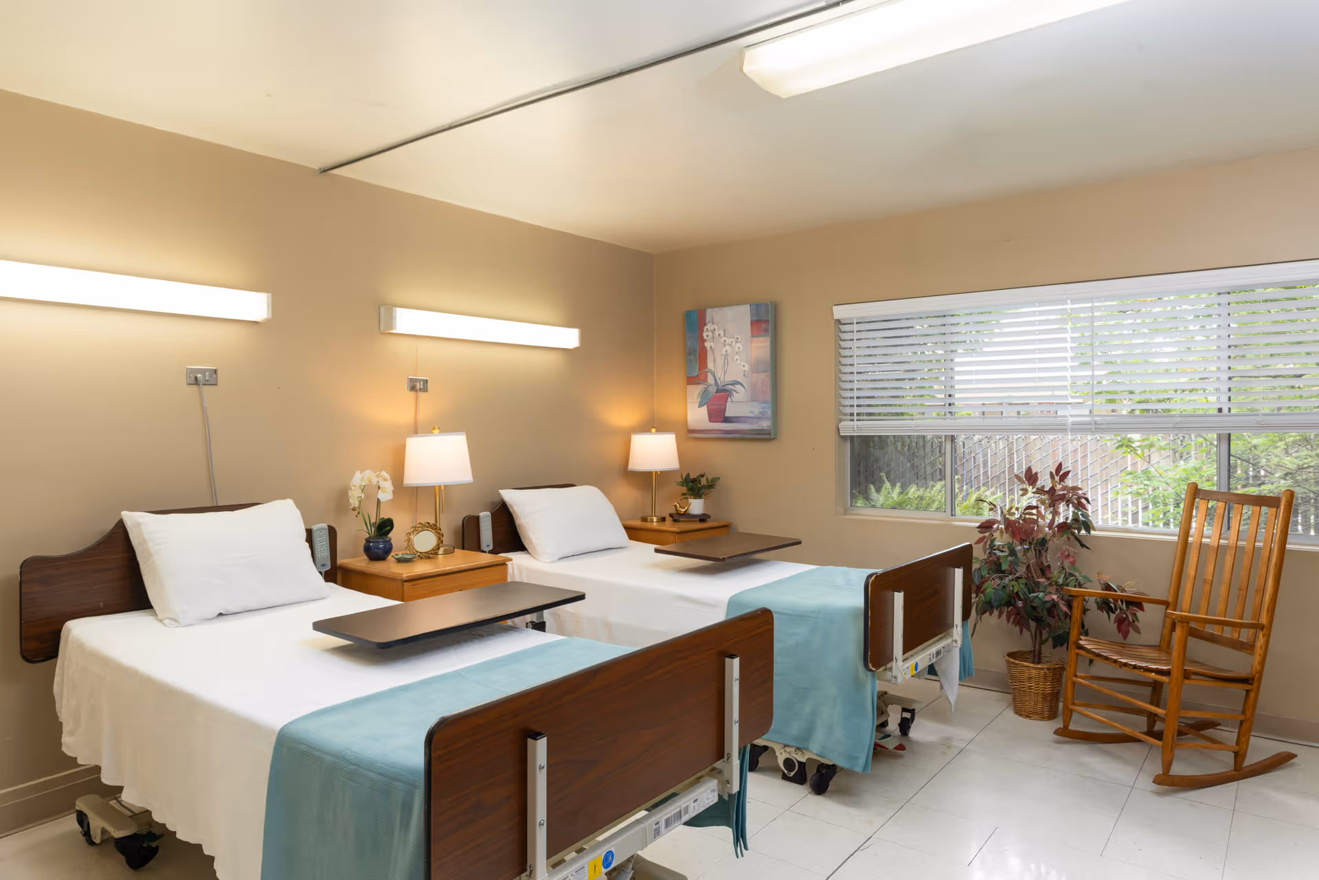 Two hospital beds with white linens sit side by side in a bright patient room.