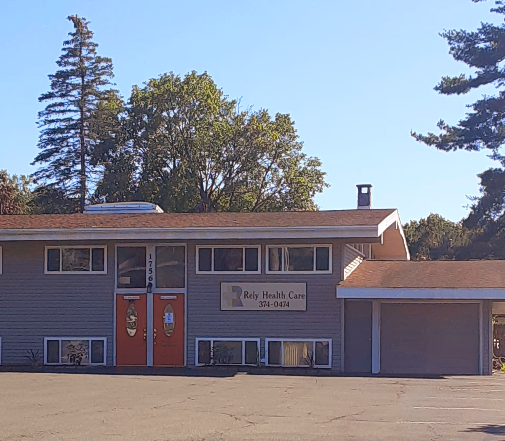 Exterior view of a single-story building with red doors and a sign.