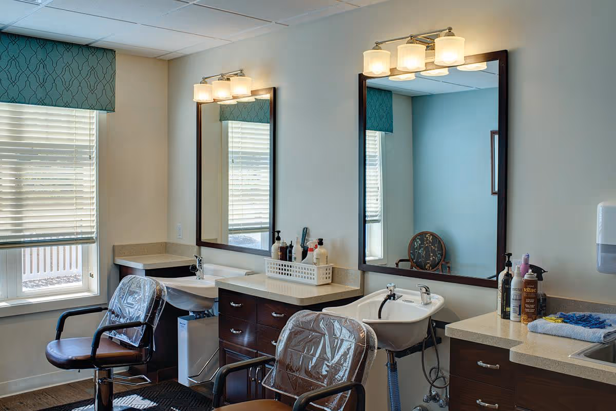 Well-lit salon area with mirrors, sinks, and chairs inside a Cedar Community Memory Care facility.