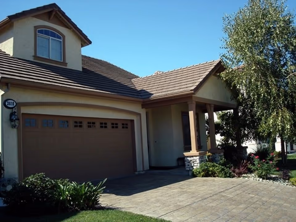 Front exterior of a suburban house showing a garage, driveway, covered porch, and landscaping.