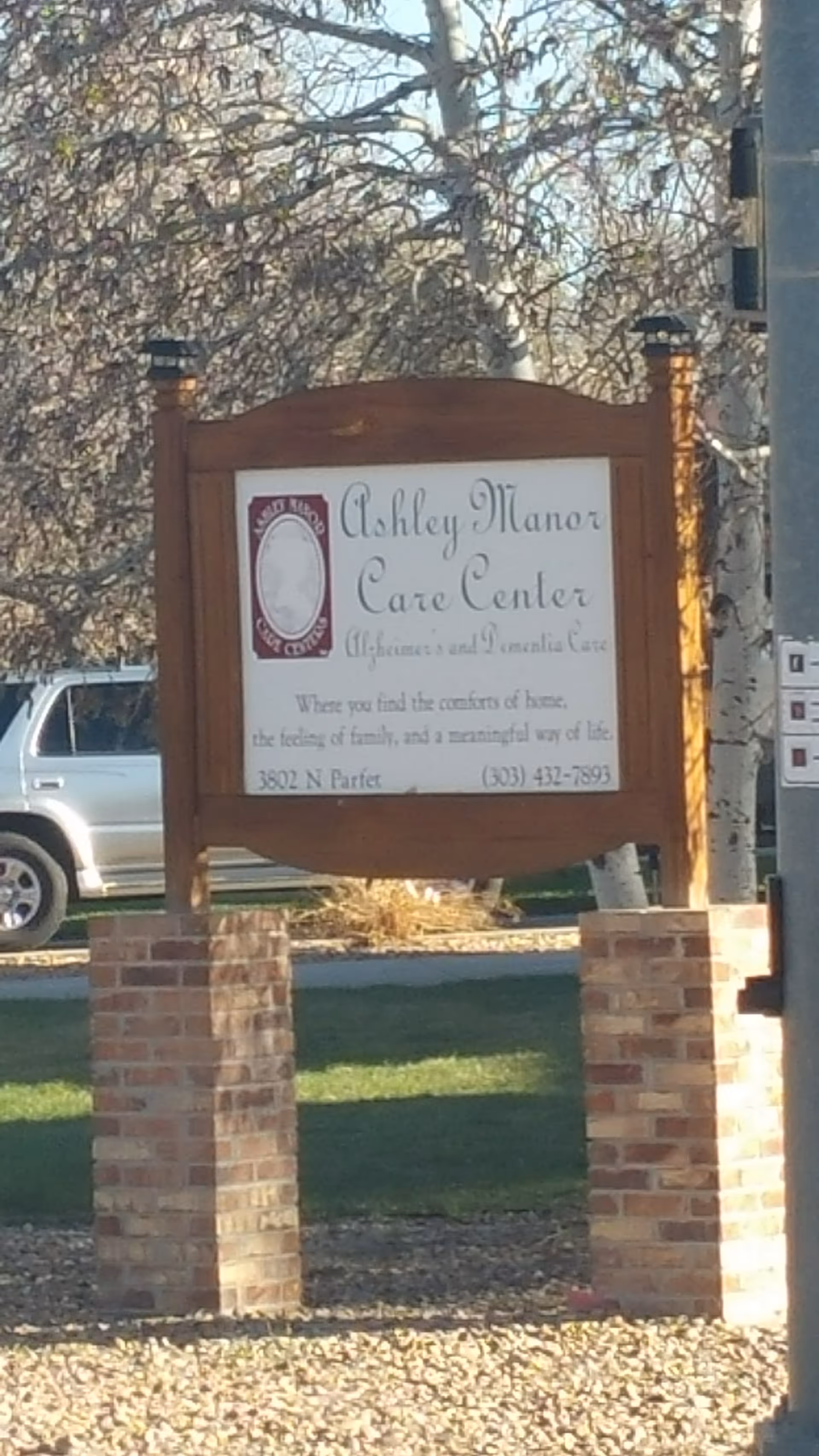 Outdoor sign for Ashley Manor Care Center between brick pillars.