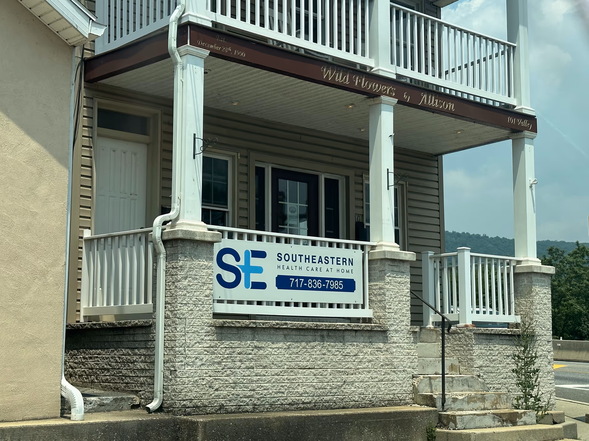 Exterior view of a two-story building with a porch and a health care sign.