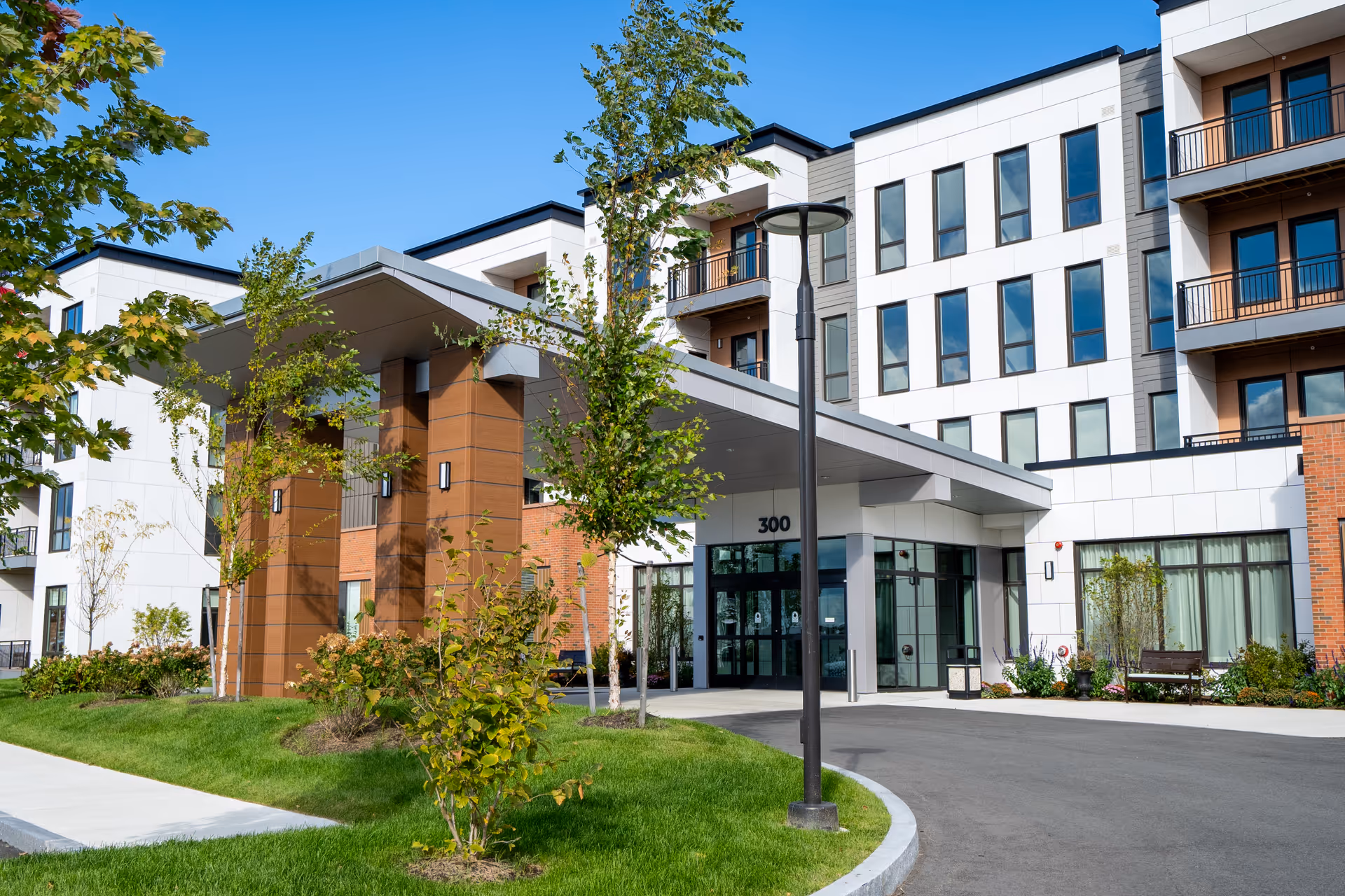 Modern senior living facility exterior with a covered entrance and landscaped front.