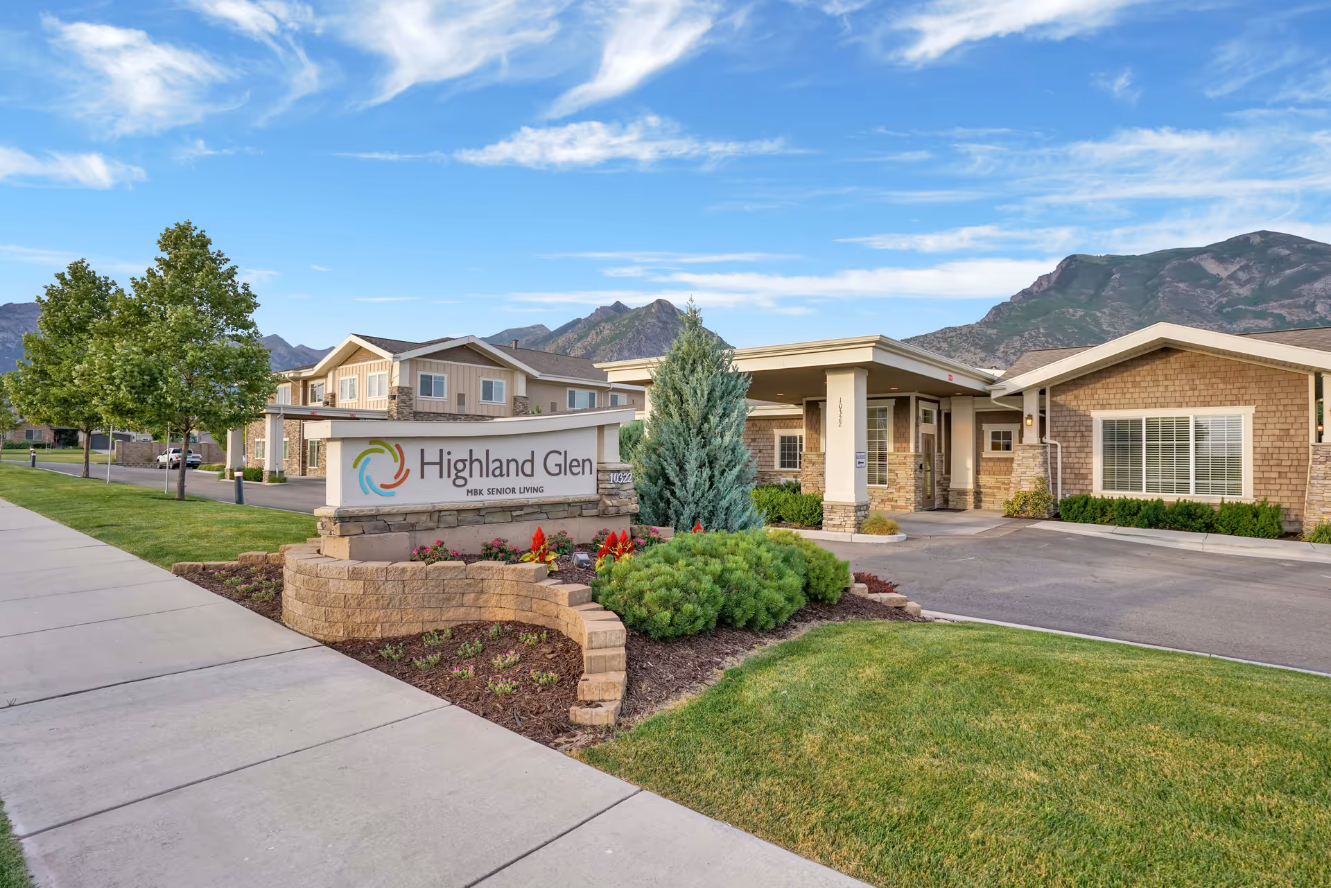 Front view of Highland Glen senior living facility with sign, driveway, and landscaping.