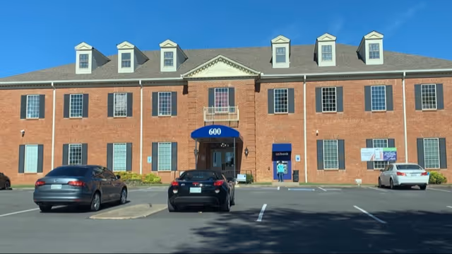 Brick building front with blue awning and parked cars