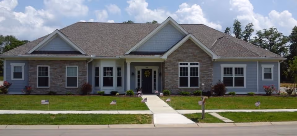 Single-story senior living facility with stone facade, manicured lawn, and front entrance.